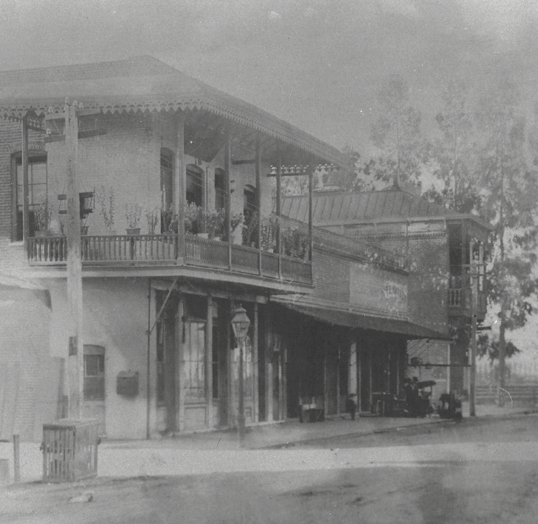 A black and white photograph depicting buildings on a tree-lined street, with Chinese-style facades and balconies