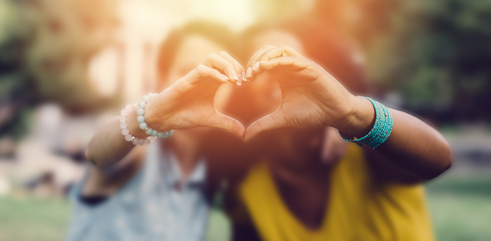 two girls making a heart with their fingers